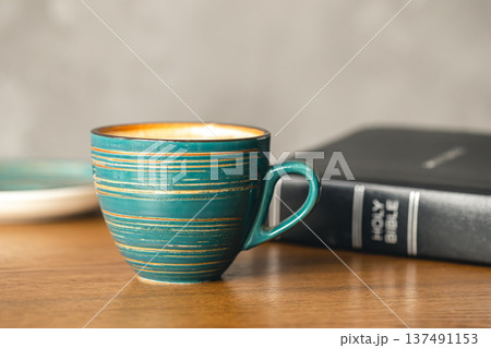 A cup of coffee and a Bible on a wooden table, close-up. A cup of coffee and a Bible on a wooden table, close-up. 137491153