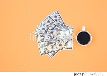 Cup of coffee and dollar bills on a orange background, flat lay. 137491165