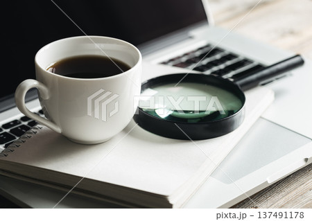 Cup of coffee, magnifier, notepad and laptop at workplace, close-up. 137491178