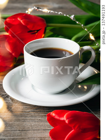 Cup of coffee and red tulips on a wooden surface. 137491193