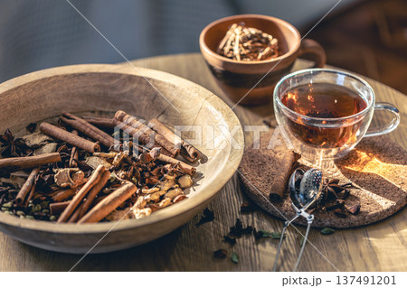 Cup of freshly brewed black tea, different types of spices on wooden table. 137491201