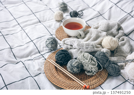 A cup of tea, knitting threads and knitted elements in the bed. A cup of tea, knitting threads and knitted elements in the bed. 137491250