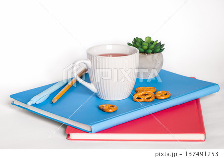 A cup of tea and notebooks on a white background, isolated, copy space. A cup of tea and notebooks on a white background, isolated, copy space. 137491253