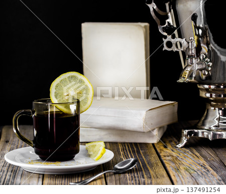Cup of tea and an old samovar on wood background Cup of tea and an old samovar on wood background 137491254