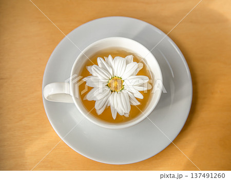 Cup of tea with chamomile flower on a wooden background, close up. Cup of tea with chamomile flower on a wooden background, close up. 137491260