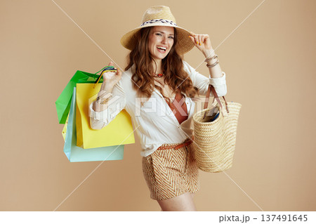 happy trendy woman in white blouse and shorts isolated on beige 137491645