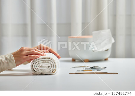 Woman enjoying a self-care beauty routine with a hand on a rolled white towel Woman enjoying a self-care beauty routine with a hand on a rolled white towel 137491774