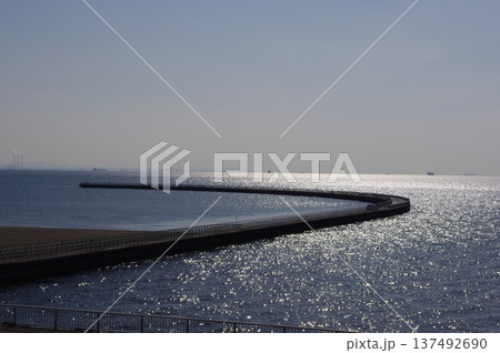 キラキラと輝く海面に続く長い堤防と水平線の風景 137492690