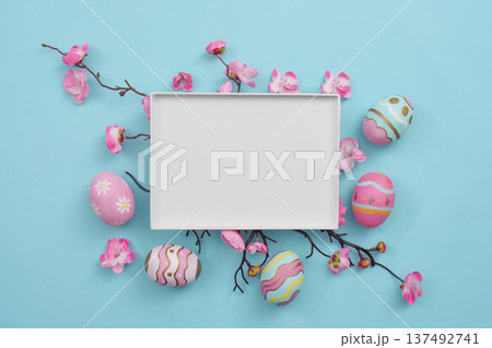 Easter Display. Decorative eggs and flowers around empty frame on blue background. 137492741