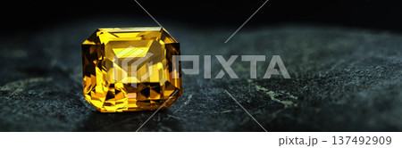 Banner with copy space. A yellow gemstone sits on a dark surface Banner with copy space. A yellow gemstone sits on a dark surface 137492909