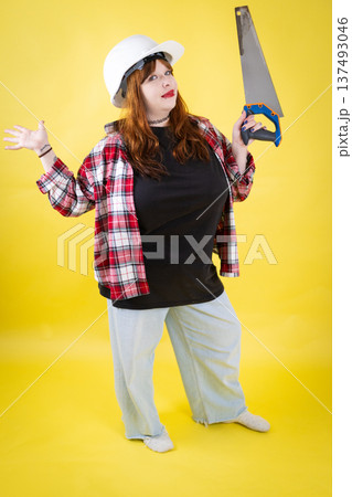 Woman builder holding handsaw and shrugging gesture 137493046