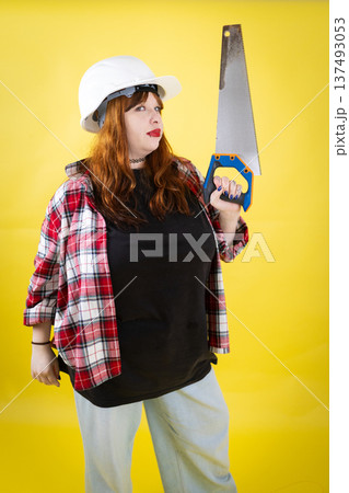 Confident young woman holding saw ready for building Confident young woman holding saw ready for building 137493053