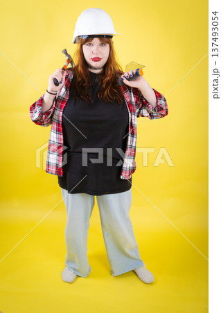 Woman posing with construction tools wearing hard hat 137493054