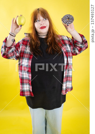 Young woman choosing between healthy apple and unhealthy donut Young woman choosing between healthy apple and unhealthy donut 137493127