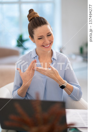 Smiling cute young woman explaining something on video call by sign language 137494277