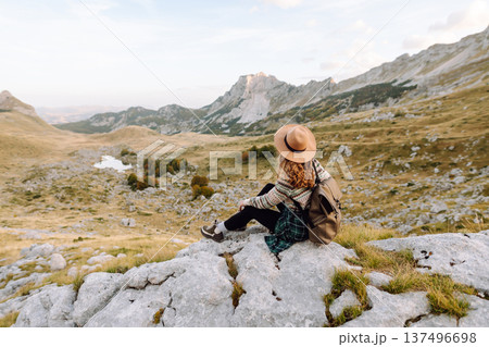 Happy woman stands on rocky terrain, gazing out at breathtaking landscape before her. Lifestyle. Happy woman stands on rocky terrain, gazing out at breathtaking landscape before her. Lifestyle. 137496698