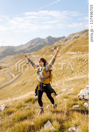 Traveler woman with a bright yellow backpack strolls through golden meadows. Active lifestyle Traveler woman with a bright yellow backpack strolls through golden meadows. Active lifestyle 137496705