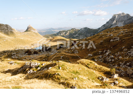 Golden sunlight illuminates vast mountain landscape with rolling hills and rocky outcrops in sunset 137496852