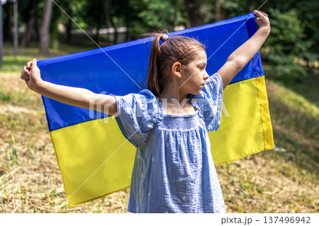 Young girl holding Ukrainian flag in park, showing patriotism and hope on a sunny day Young girl holding Ukrainian flag in park, showing patriotism and hope on a sunny day 137496942