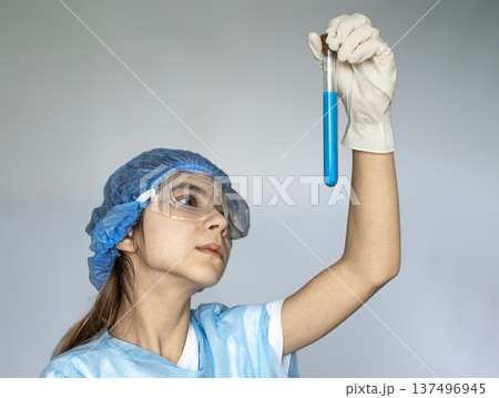 Young scientist in protective gear examining a blue solution in a test tube during research Young scientist in protective gear examining a blue solution in a test tube during research 137496945