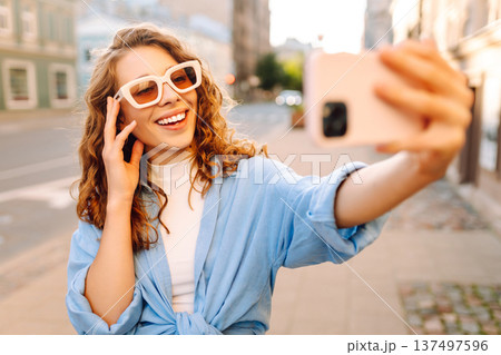 Beautiful woman traveler using phone, taking selfie, walking on the old town street. Blogging Beautiful woman traveler using phone, taking selfie, walking on the old town street. Blogging 137497596