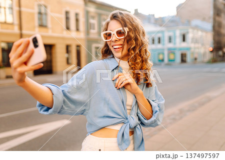 Beautiful woman traveler using phone, taking selfie, walking on the old town street. Blogging 137497597
