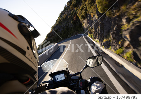 Driver riding motorcycle on empty asphalt road, handlebars view , spring mountains Driver riding motorcycle on empty asphalt road, handlebars view , spring mountains 137498795