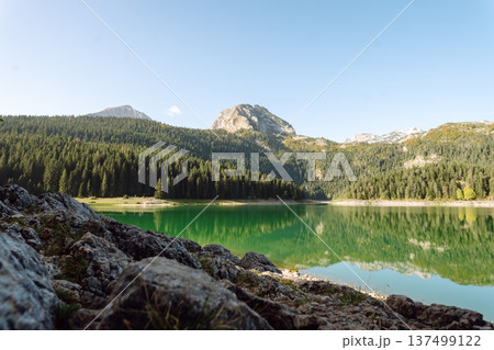 Incredible view in mountains of the lake. Rocky shore of mountain lake in the morning. 137499122