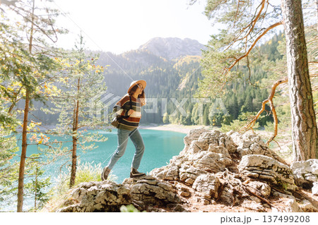 Young woman traveler enjoys fresh air and a beautiful view of the lake and mountains. Active life Young woman traveler enjoys fresh air and a beautiful view of the lake and mountains. Active life 137499208