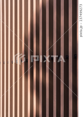ダークブラウンのスラットパネル外壁と光と影のテクスチャ背景 137499273