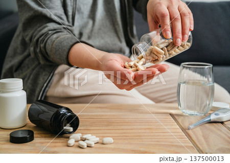 Sickness and health issues. Woman holding a pill bottle at home, healthy care and treatment concept. Sickness and health issues. Woman holding a pill bottle at home, healthy care and treatment concept. 137500013