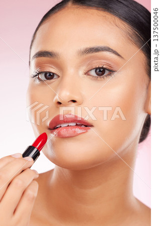 Portrait, beauty and lipstick with a woman closeup on a pink background in studio for luxury cosmetics. Aesthetic, makeup or product with a young model getting ready to apply red lipgloss to her face Portrait, beauty and lipstick with a woman closeup on a pink background in studio for luxury cosmetics. Aesthetic, makeup or product with a young model getting ready to apply red lipgloss to her face 137500046