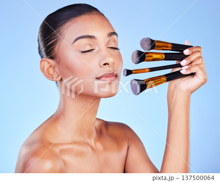 Woman, eyes closed and beauty, makeup and brush for foundation with cosmetics isolated on blue background. Indian model, wellness and cosmetology with tools or equipment, skin and shine in studio Woman, eyes closed and beauty, makeup and brush for foundation with cosmetics isolated on blue background. Indian model, wellness and cosmetology with tools or equipment, skin and shine in studio 137500064