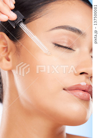 Skincare, beauty and woman with serum in pipette for anti aging or skin glow on blue background. Cosmetics, facial detox and face of model with solution or collagen product for dermatology in studio. 137500081