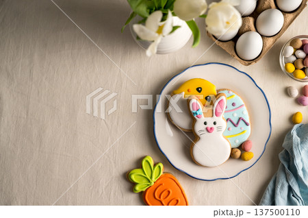 Easter festive background. Colourful easter cookies bunny, egg, chick and carrot. White spring tulips bouquet. 137500110