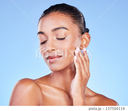 Woman, touching face and natural beauty, skincare and cosmetic care isolated on blue background, Indian model with satisfaction, wellness and calm, zen and dermatology with skin glow in a studio 137500119