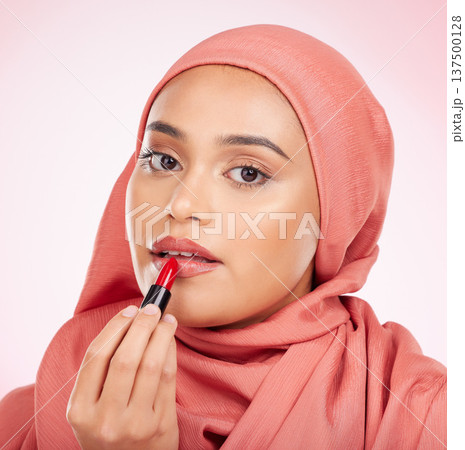 Portrait, beauty or lipstick with an arab woman closeup in studio on a pink background for cosmetics. Face, makeup and muslim with a confident young model in an hijab to apply a product for red color 137500128
