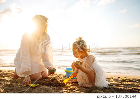 Mother and daughter enjoying time at the beach. Plays toys. Family vacation. 137500144