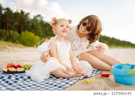 Mother and daughter enjoying time at the beach. Plays toys. Family vacation. 137500145