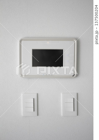 It's a white wall with an intercom and a switch. It's a white wall with an intercom and a switch. 137500204