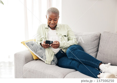 Happy black woman, smartphone and typing on sofa for social media post, digital contact and reading notification. Cellphone, mobile games and scroll online shopping app to search subscription at home 137500250