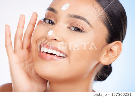 Portrait, beauty and woman with cream, skincare and dermatology on blue studio background. Face, person and model with beauty, lotion or wellness with shine, smile or glow with aesthetic or creme 137500281