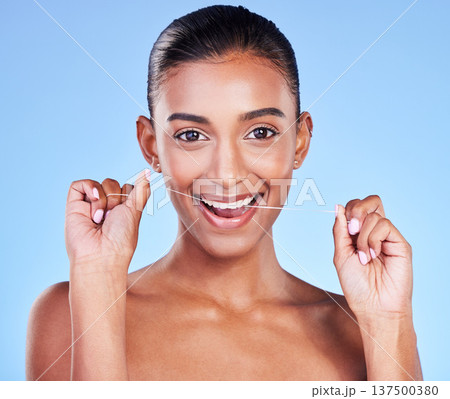 Woman, portrait and floss teeth in studio for healthy dental care, gum gingivitis and plaque on blue background. Happy indian model and oral thread for cleaning mouth, fresh breath and tooth hygiene 137500380