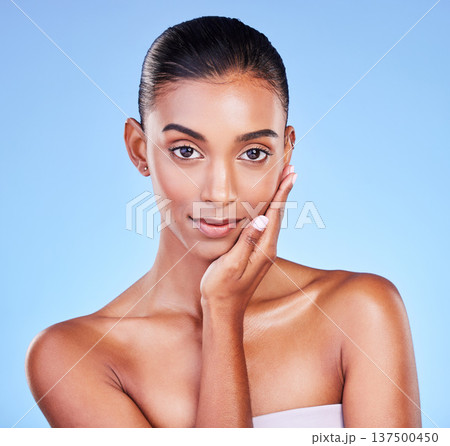 Skincare, woman and hand on face in studio for wellness, cosmetic or treatment on blue background. Portrait, beauty and lady model touching glow, skin or smooth, dermatology or results satisfaction 137500450