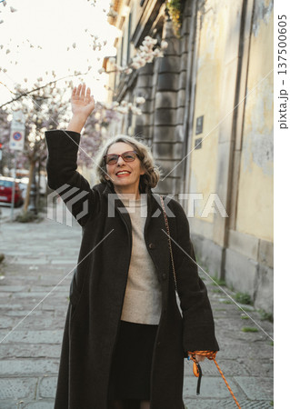 Woman Smiling and Waving on an Urban Street Woman Smiling and Waving on an Urban Street 137500605