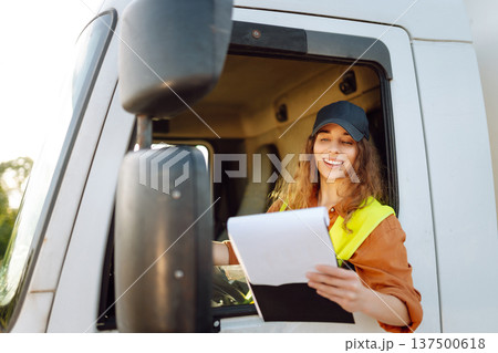 Portrait of beautiful young woman professional truck driver checking shipment list on a -parking lot Portrait of beautiful young woman professional truck driver checking shipment list on a -parking lot 137500618