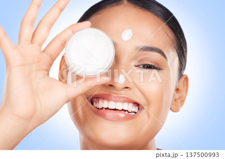 Portrait, happy woman and cream container for face, aesthetic skincare and shine on blue background. Young model, facial beauty and moisturizer jar for sunscreen, cosmetics and dermatology in studio Portrait, happy woman and cream container for face, aesthetic skincare and shine on blue background. Young model, facial beauty and moisturizer jar for sunscreen, cosmetics and dermatology in studio 137500993