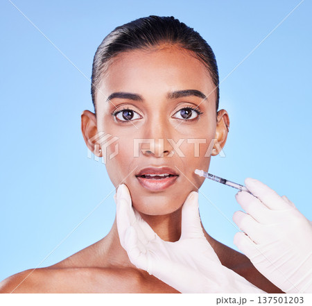 Surprise, woman face and plastic surgery, beauty and injection in portrait, doctor hands on blue background. Cosmetic treatment, wow and liquid collagen in needle syringe with skincare in a studio 137501203