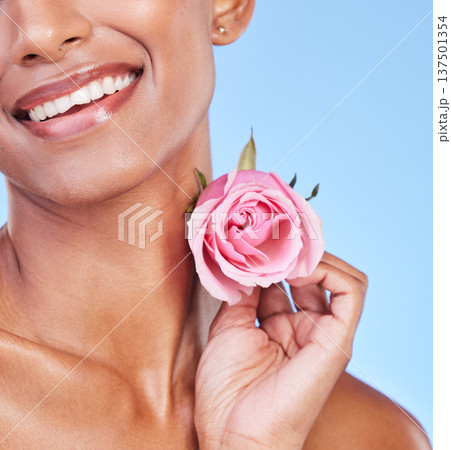 Woman with rose, closeup and natural beauty with sustainable skincare isolated on blue background. Wellness, skin glow and eco friendly cosmetics with pink flower, product and nature in a studio 137501354