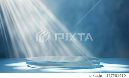 Sun rays shine through a window, casting light on a clear glass plate positioned on a blue surface, creating a serene morning ambiance. Sun rays shine through a window, casting light on a clear glass plate positioned on a blue surface, creating a serene morning ambiance. 137501410